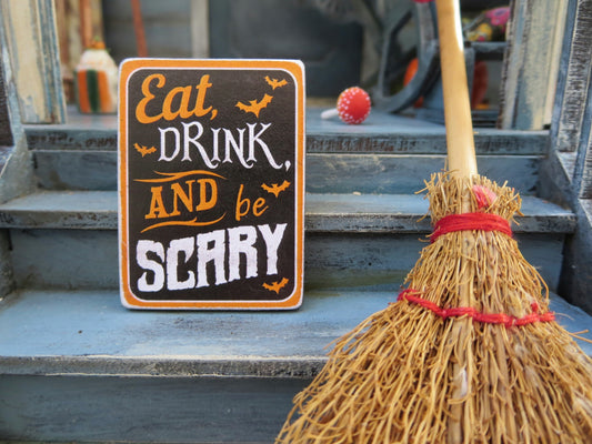 Chalk sign saying "Eat Drink and be Scary" with a broom stick