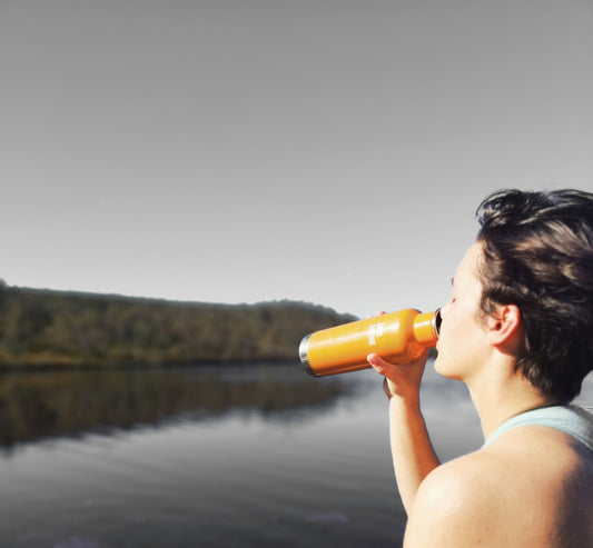 Woman drinking water by a lake